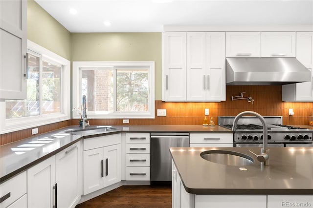 kitchen featuring stainless steel appliances, dark countertops, extractor fan, a sink, and a wealth of natural light