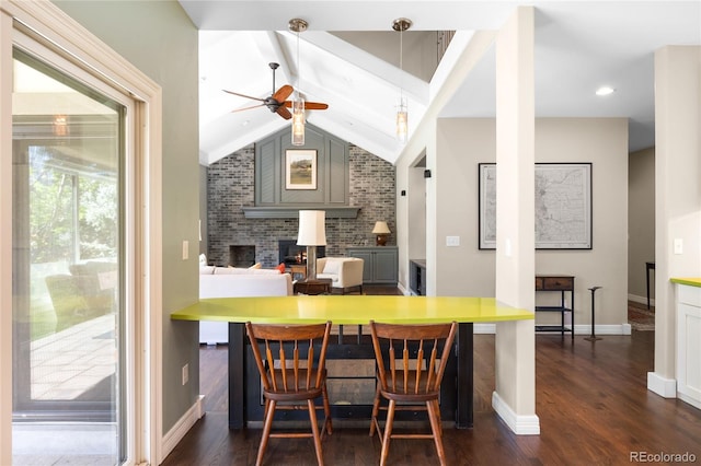 kitchen with a fireplace, a ceiling fan, lofted ceiling with beams, and dark wood-style flooring