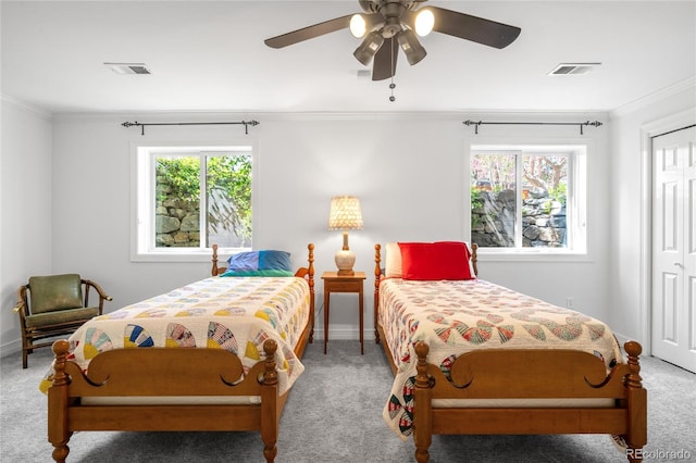 carpeted bedroom featuring baseboards, crown molding, visible vents, and a closet