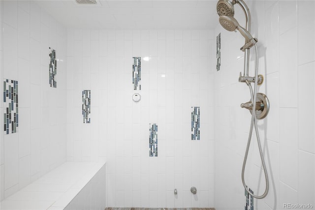 bathroom with a tile shower and visible vents