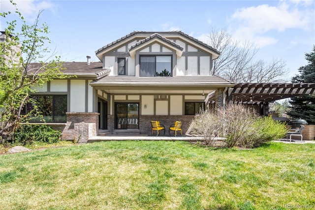 back of property with a tiled roof, a pergola, brick siding, a yard, and stucco siding