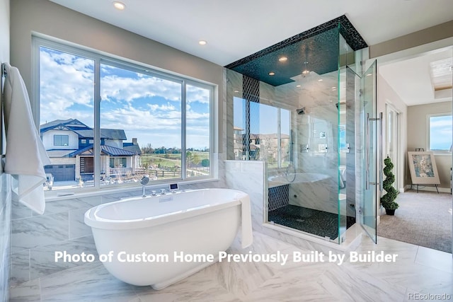 bathroom featuring tile walls, a soaking tub, a healthy amount of sunlight, and a shower stall