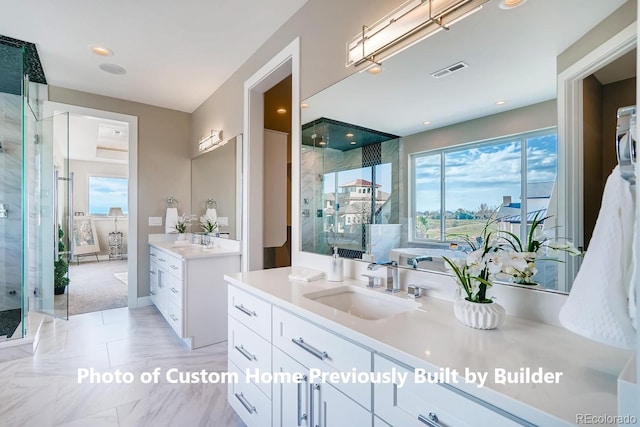 full bath with a stall shower, visible vents, two vanities, and a sink