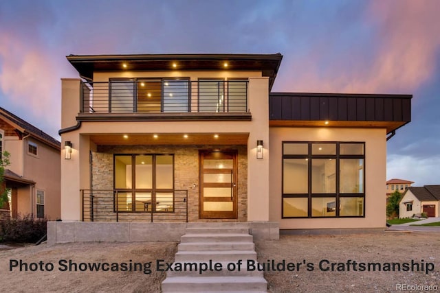 contemporary house with stucco siding, covered porch, a standing seam roof, metal roof, and a balcony