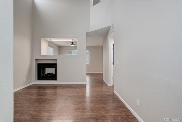15828 Greenstone Ln, Parker, CO 80134 - unfurnished living room with a ceiling fan, dark wood-style flooring, a multi sided fireplace, and baseboards