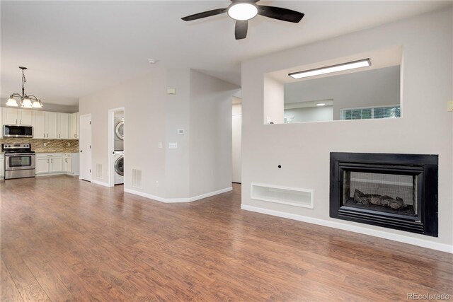 15828 Greenstone Ln, Parker, CO 80134 - unfurnished living room featuring stacked washer and clothes dryer, a ceiling fan, dark wood-style flooring, a multi sided fireplace, and baseboards