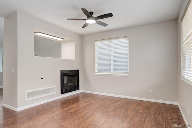15828 Greenstone Ln, Parker, CO 80134 - unfurnished living room featuring a glass covered fireplace, wood finished floors, baseboards, and a ceiling fan