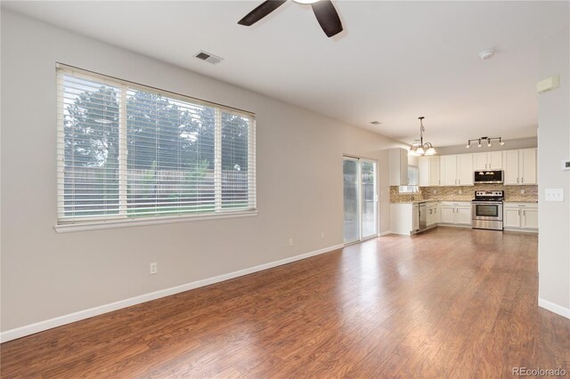 15828 Greenstone Ln, Parker, CO 80134 - unfurnished living room featuring healthy amount of natural light, a ceiling fan, a chandelier, and dark wood-style floors