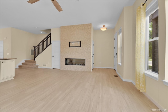 5154 Taft Ct, Wheat Ridge, CO 80033 - unfurnished living room with light wood-type flooring, stairs, ceiling fan, and a large fireplace