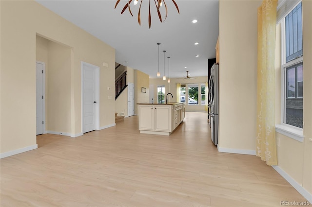 5154 Taft Ct, Wheat Ridge, CO 80033 - kitchen with open floor plan, light wood-style flooring, a center island with sink, hanging light fixtures, and stainless steel fridge