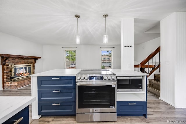 1549 S Evanston St, Aurora, CO 80012 - kitchen with stainless steel appliances, blue cabinets, a brick fireplace, and light wood finished floors