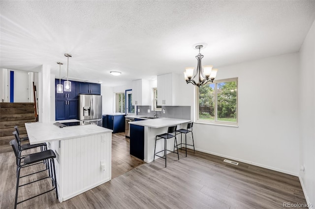 1549 S Evanston St, Aurora, CO 80012 - kitchen with blue cabinets, stainless steel fridge, a peninsula, a kitchen bar, and light countertops