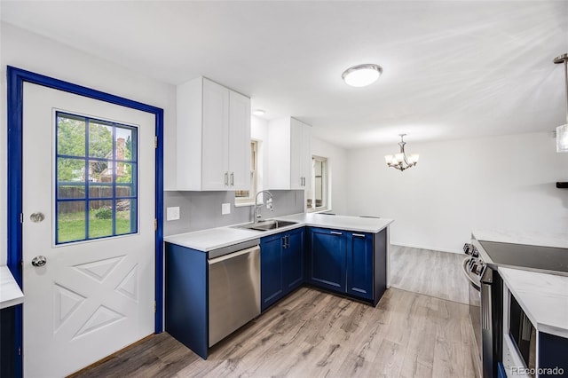 1549 S Evanston St, Aurora, CO 80012 - kitchen with stainless steel appliances, a sink, blue cabinetry, a peninsula, and a chandelier