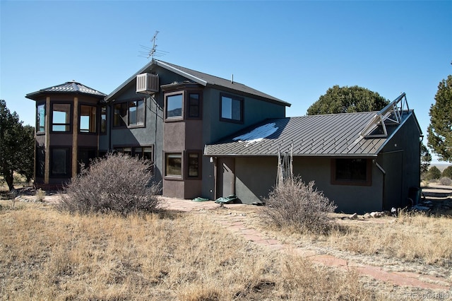 1507 Wagon Wheel Rd, Crestone, CO 81131 - back of house featuring stucco siding, metal roof, a standing seam roof, and a wall unit AC