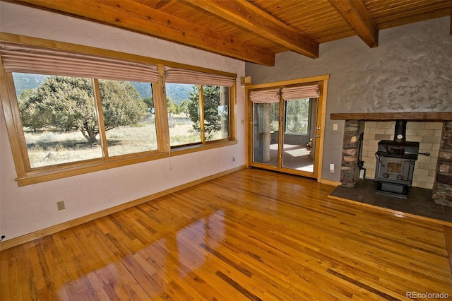 1507 Wagon Wheel Rd, Crestone, CO 81131 - unfurnished living room with baseboards, hardwood / wood-style floors, beam ceiling, wooden ceiling, and a wood stove