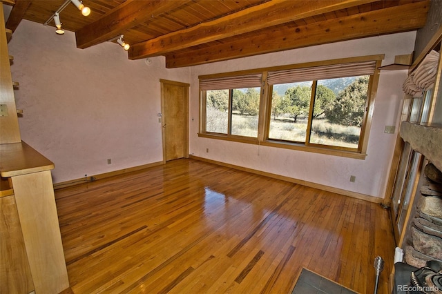 1507 Wagon Wheel Rd, Crestone, CO 81131 - unfurnished living room featuring beamed ceiling, track lighting, hardwood / wood-style floors, wooden ceiling, and baseboards