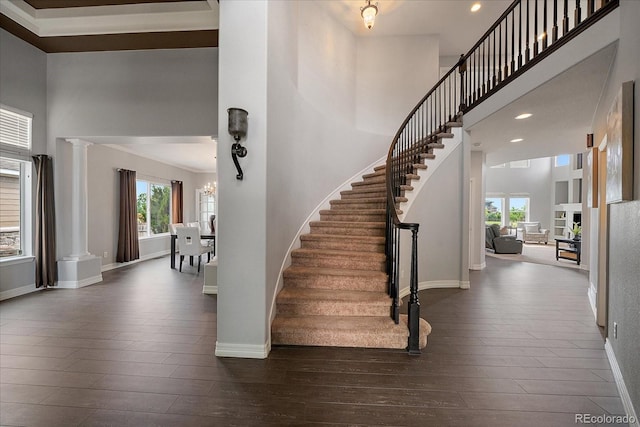 11691 Riverdale Dr, Parker, CO 80138 - stairs featuring wood-type flooring, ornate columns, a towering ceiling, plenty of natural light, and recessed lighting