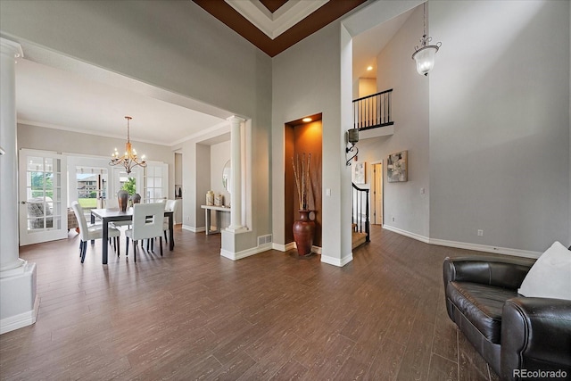 11691 Riverdale Dr, Parker, CO 80138 - dining room featuring a chandelier, decorative columns, dark wood finished floors, ornamental molding, and a towering ceiling