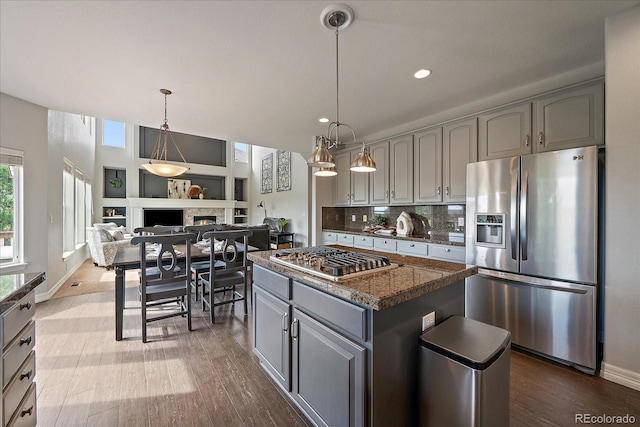 11691 Riverdale Dr, Parker, CO 80138 - kitchen featuring stainless steel appliances, gray cabinets, dark wood-style floors, a kitchen island, and a lit fireplace