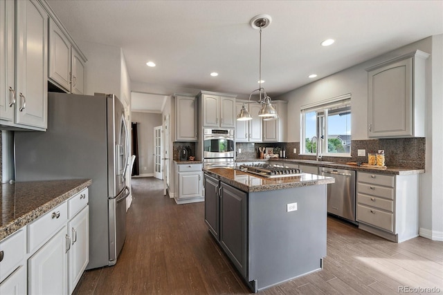 11691 Riverdale Dr, Parker, CO 80138 - kitchen featuring stainless steel appliances, tasteful backsplash, dark wood-style flooring, a center island, and recessed lighting
