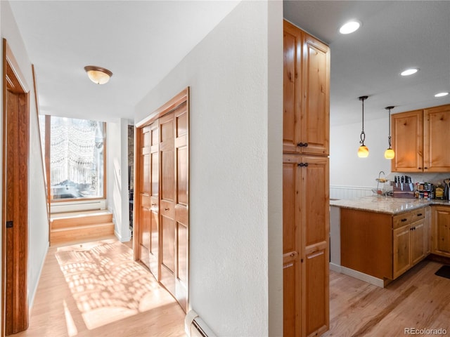 hall with light wood-style flooring, a baseboard heating unit, and recessed lighting