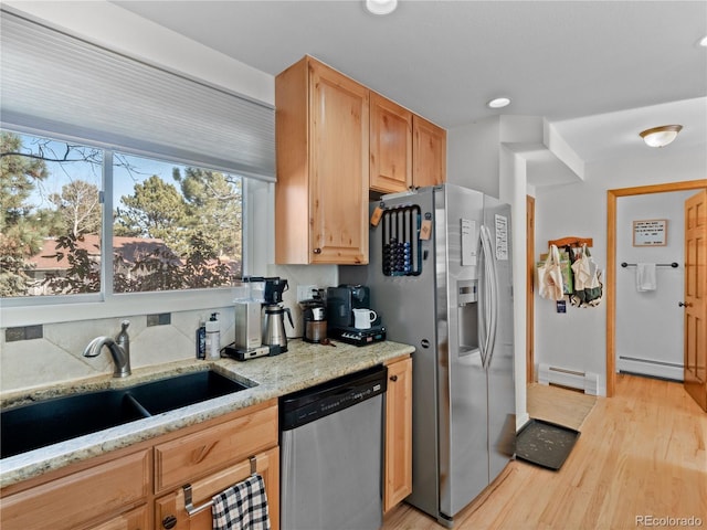 kitchen with appliances with stainless steel finishes, a baseboard radiator, a sink, and light wood finished floors