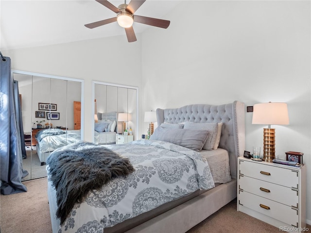 carpeted bedroom featuring multiple closets, vaulted ceiling, and ceiling fan