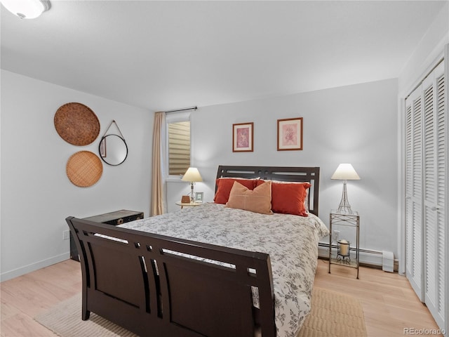 bedroom with light wood-type flooring, a baseboard radiator, a closet, and baseboards