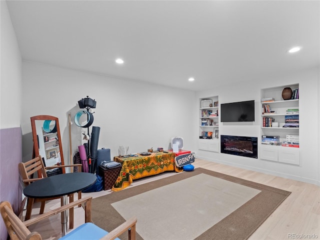 playroom with recessed lighting, built in features, wood finished floors, and a glass covered fireplace