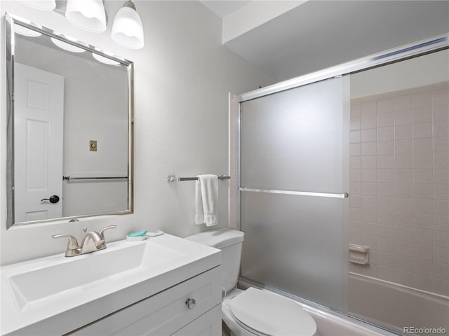 full bath featuring combined bath / shower with glass door, vanity, and toilet