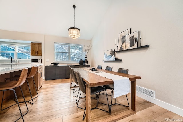 6443 S Florence Way, Englewood, CO 80111 - dining space featuring light wood-style floors, a chandelier, and high vaulted ceiling
