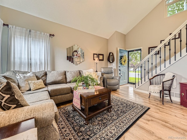 living area with high vaulted ceiling, stairway, wood finished floors, and baseboards
