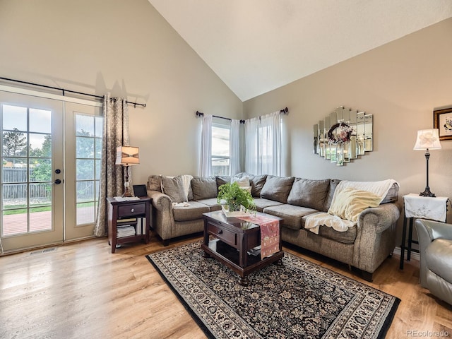 living area featuring high vaulted ceiling, french doors, and light wood-style floors
