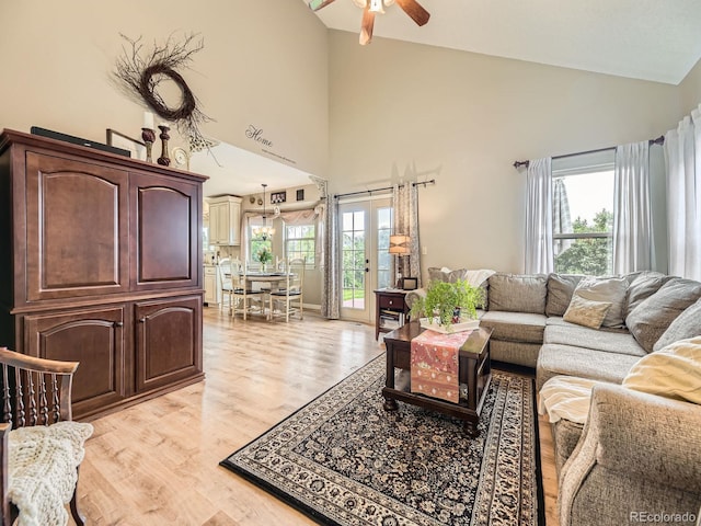 living room with ceiling fan, high vaulted ceiling, and light wood finished floors