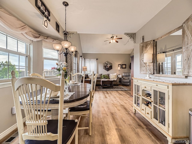 dining space with light wood-style floors, ceiling fan, lofted ceiling, and a chandelier