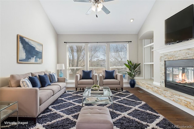 living room featuring ceiling fan, a fireplace, dark hardwood / wood-style floors, and high vaulted ceiling