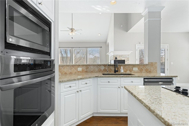 kitchen featuring sink, stainless steel appliances, light stone countertops, decorative columns, and white cabinets