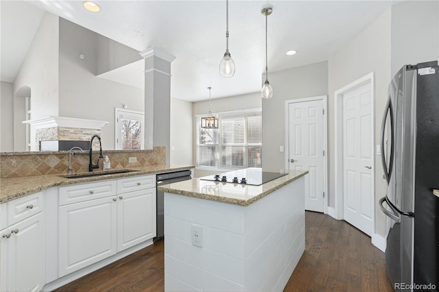 kitchen with sink, white cabinetry, light stone counters, appliances with stainless steel finishes, and pendant lighting