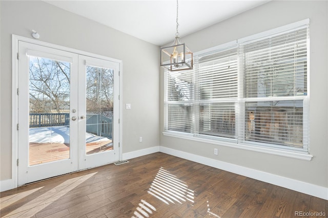 unfurnished dining area with french doors, hardwood / wood-style floors, and a notable chandelier