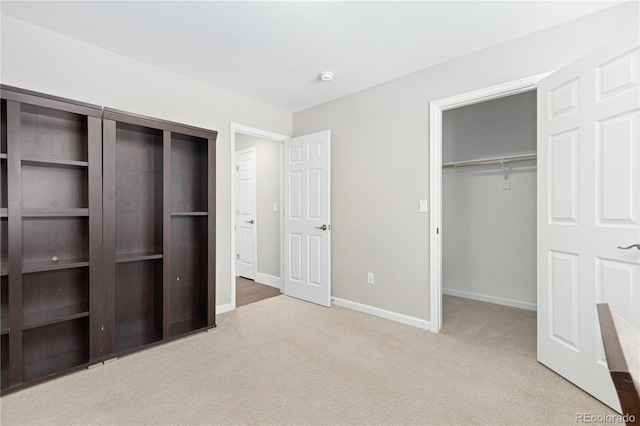 unfurnished bedroom featuring a spacious closet, light colored carpet, and a closet