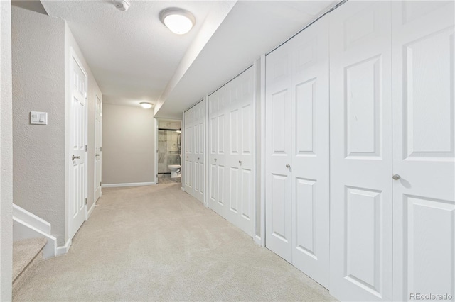 corridor featuring light carpet and a textured ceiling