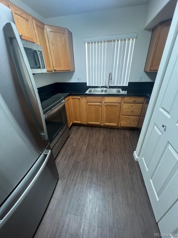 kitchen with dark hardwood / wood-style flooring, stainless steel appliances, and sink