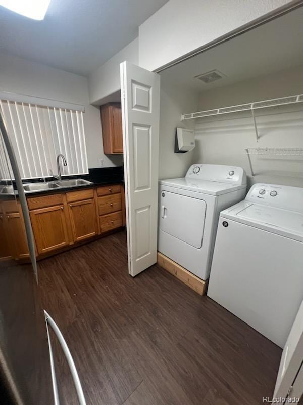 washroom featuring dark hardwood / wood-style flooring, washer and clothes dryer, and sink