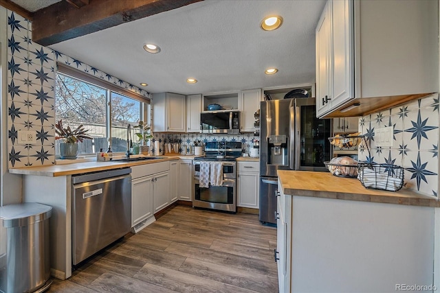 kitchen featuring dark wood-type flooring, sink, butcher block countertops, stainless steel appliances, and white cabinets