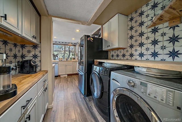 laundry area with sink, dark wood-type flooring, cabinets, independent washer and dryer, and a textured ceiling