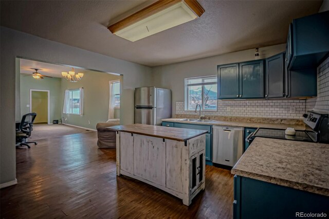 kitchen featuring blue cabinets, sink, dark hardwood / wood-style flooring, hanging light fixtures, and stainless steel appliances