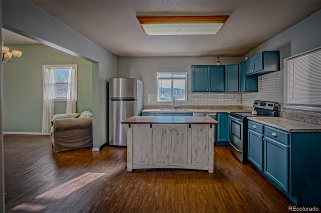 kitchen featuring appliances with stainless steel finishes, dark hardwood / wood-style floors, sink, backsplash, and blue cabinetry