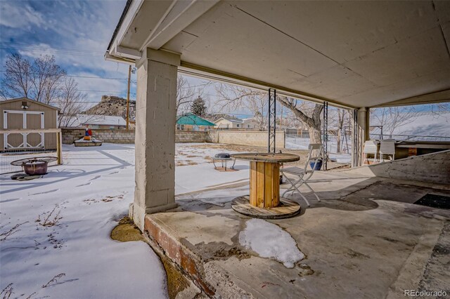 snow covered patio featuring a storage shed