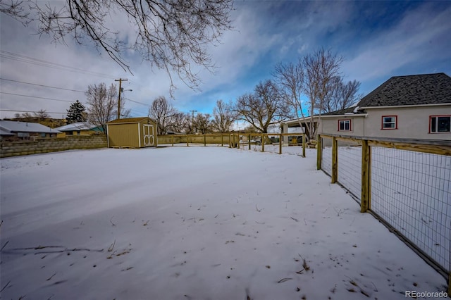 yard layered in snow featuring a shed