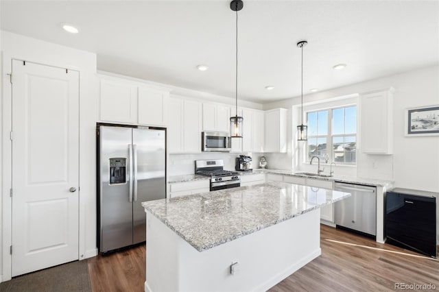 kitchen featuring white cabinetry, hanging light fixtures, a kitchen island, and appliances with stainless steel finishes